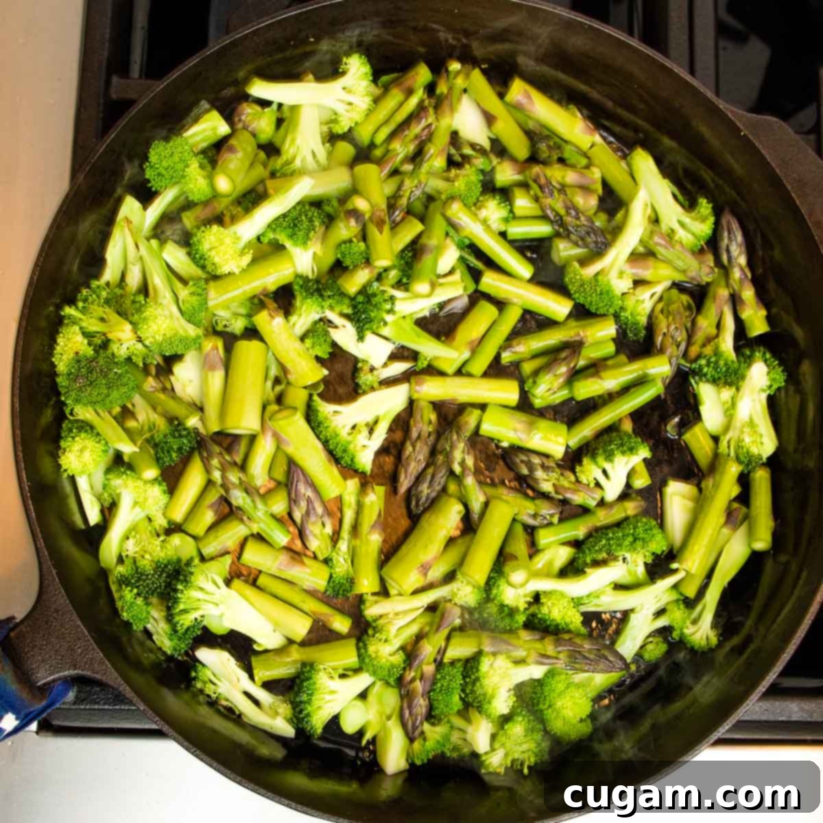 Broccoli and asparagus sautéing in a skillet.