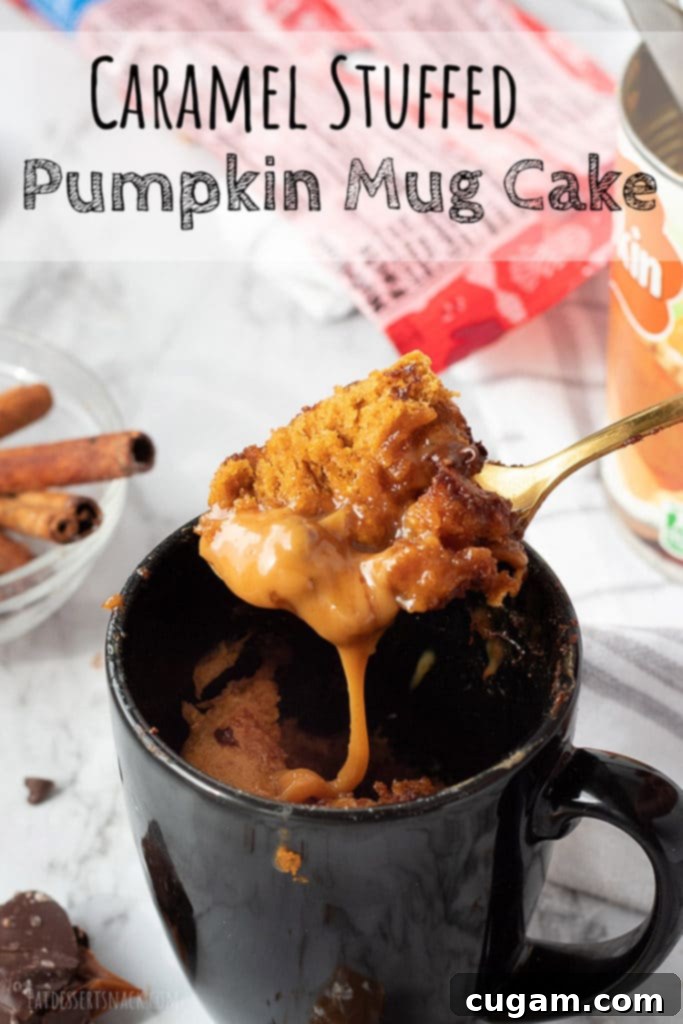 Cooked caramel stuffed pumpkin mug cake on a spoon, showcasing its fluffy texture and golden-brown top. A rich caramel center is visible.