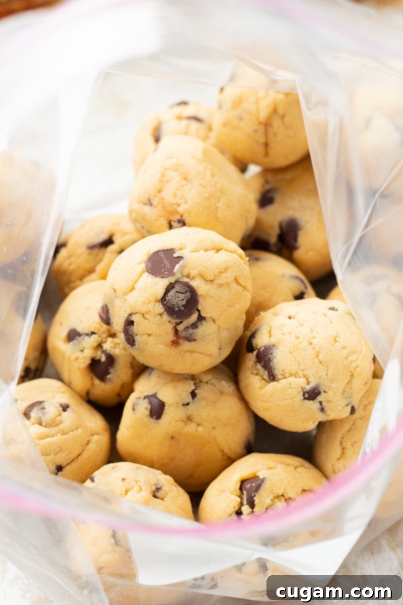 Raw, frozen chocolate chip pudding mix cookie dough balls stored in a clear freezer bag for later use.