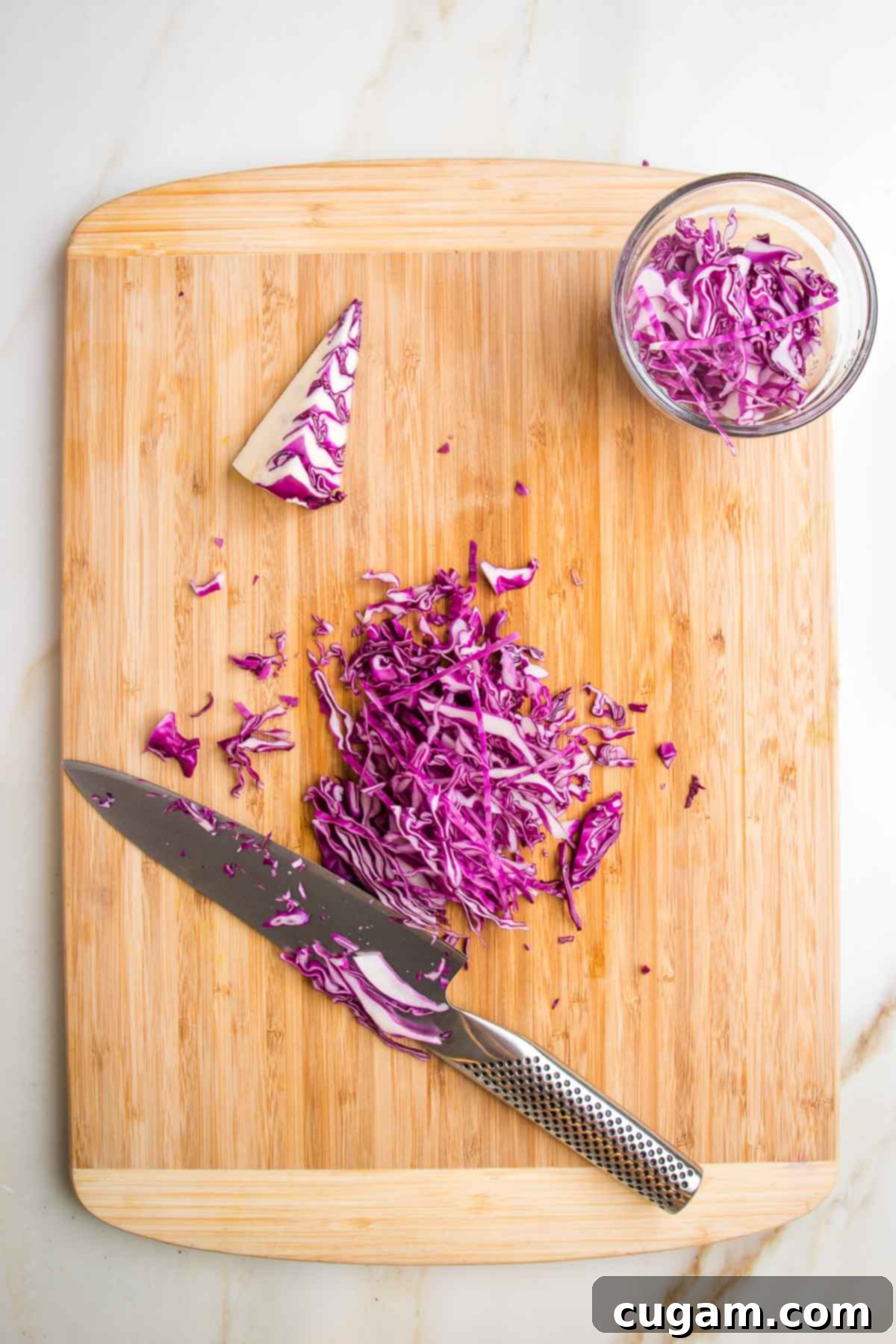 Cutting board with sharp knife showing how to cut purple cabbage.