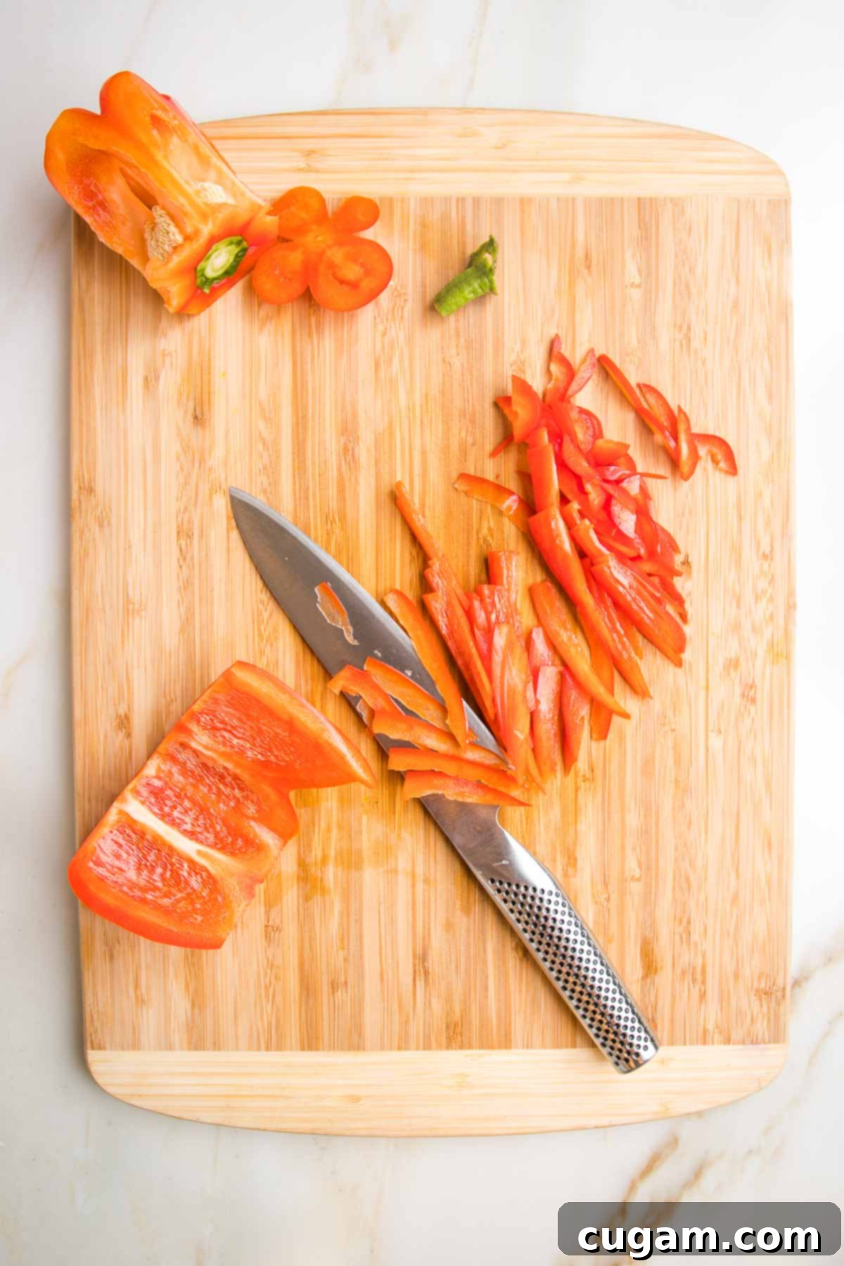 Bamboo cutting board, showing how to cut a red pepper into thin strips.