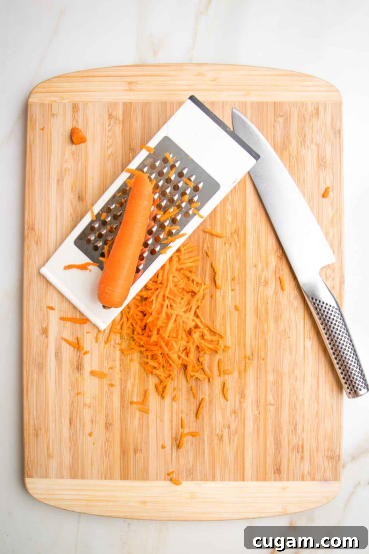 Cutting board and sharp knife, showing how to shred a carrot on the side of a box grater.
