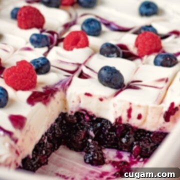 Blueberries and raspberries on whipped filling and sliced blueberry jello in white dish.