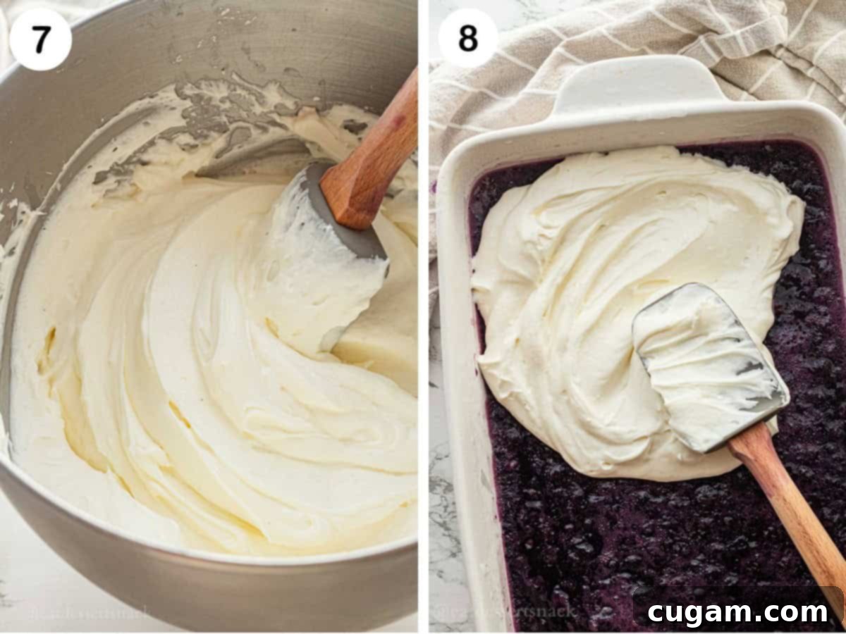 Whipped cream topping in metal mixing bowl and spatula spreading topping onto set blueberry jello.