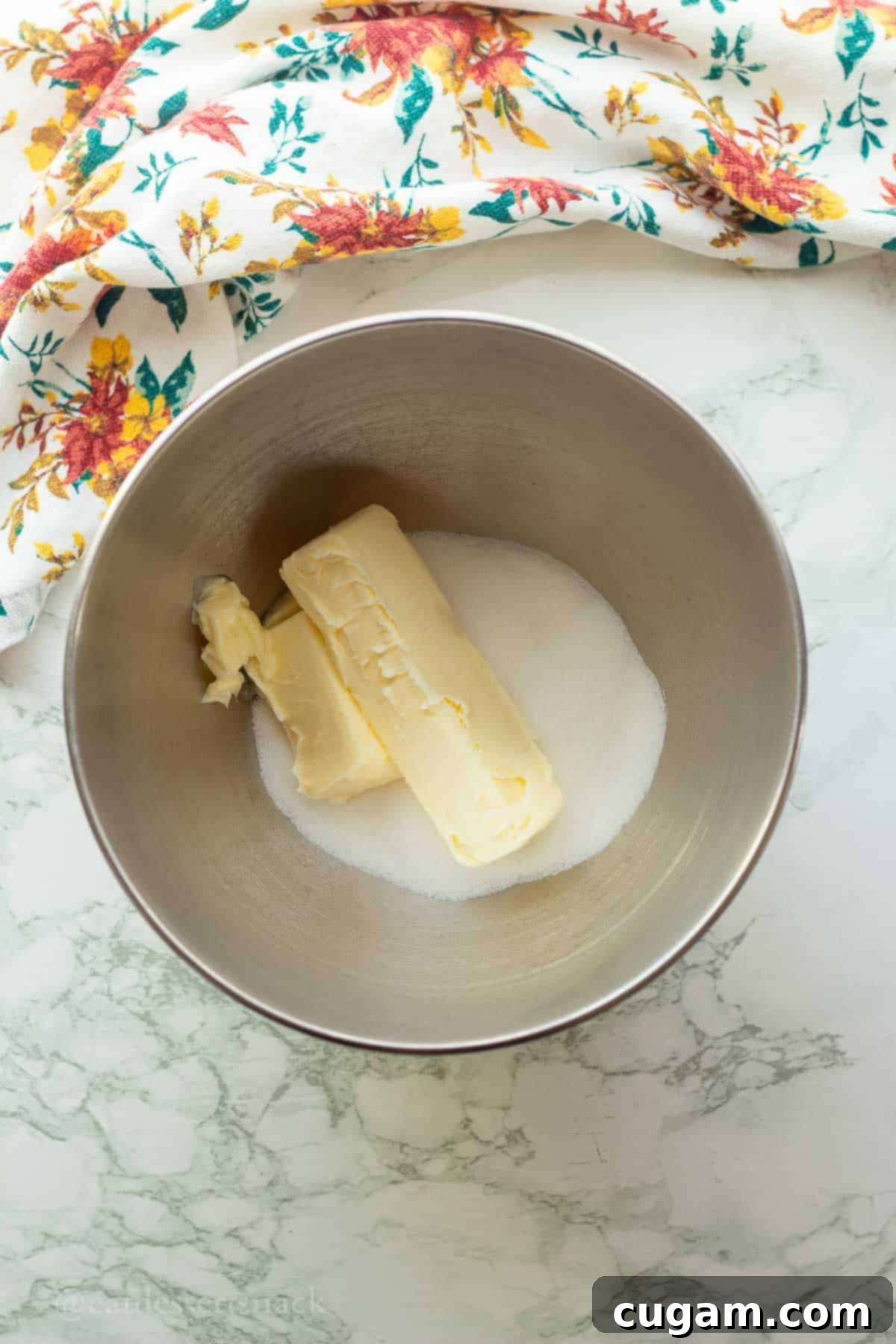 Softened butter and granulated sugar in a metal mixing bowl, ready to be creamed.