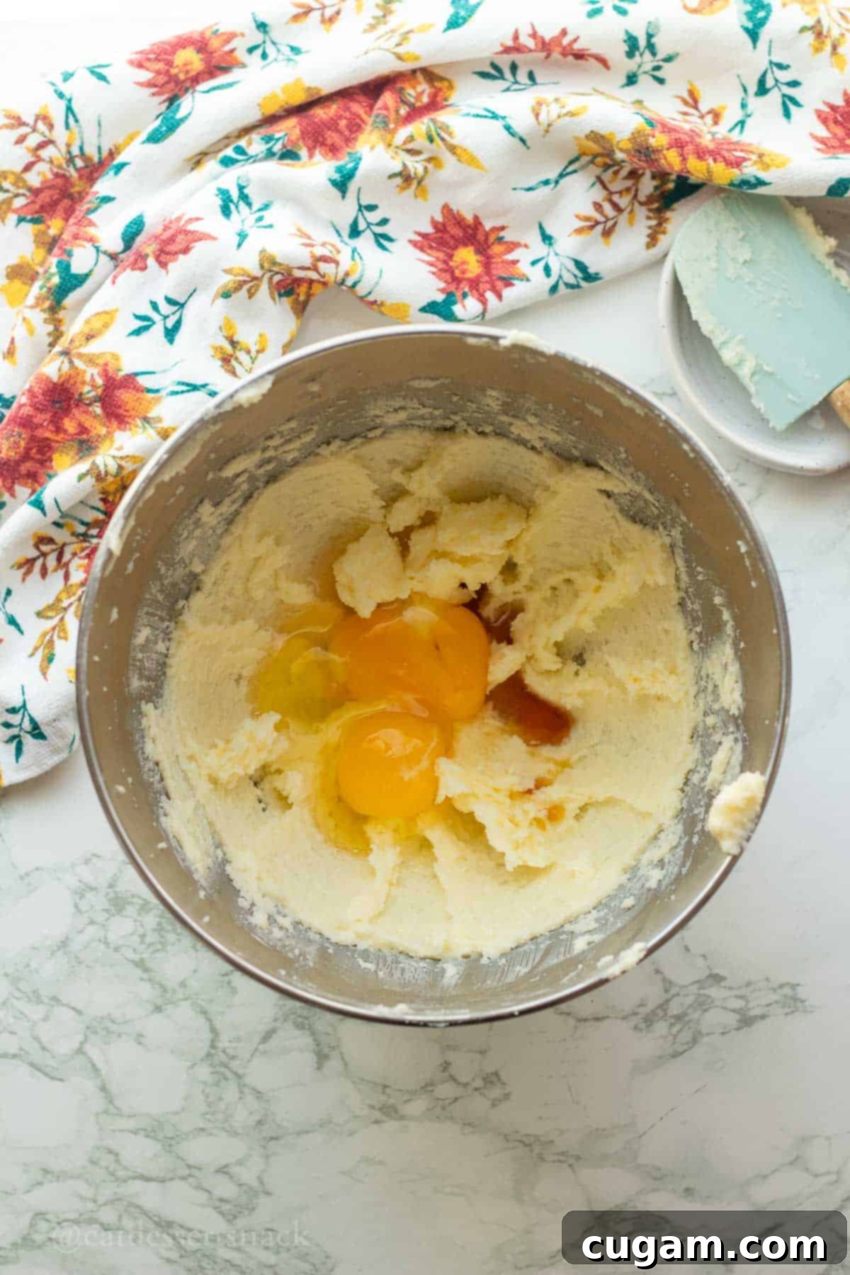 Eggs, vanilla extract, and sour cream added to the creamed butter and sugar mixture in a metal bowl.