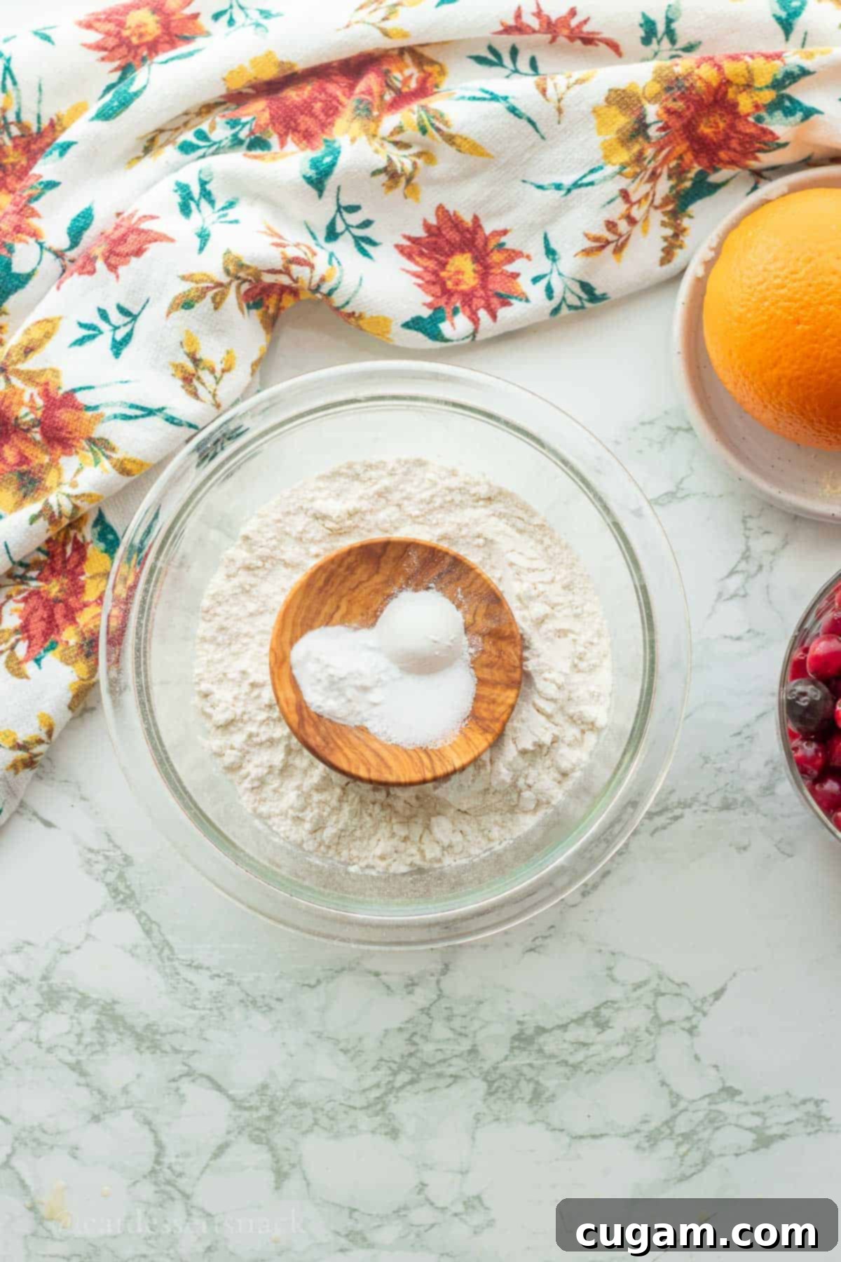 Dry ingredients for cranberry orange coffee cake – flour, salt, baking powder, and baking soda – in a clear glass bowl.
