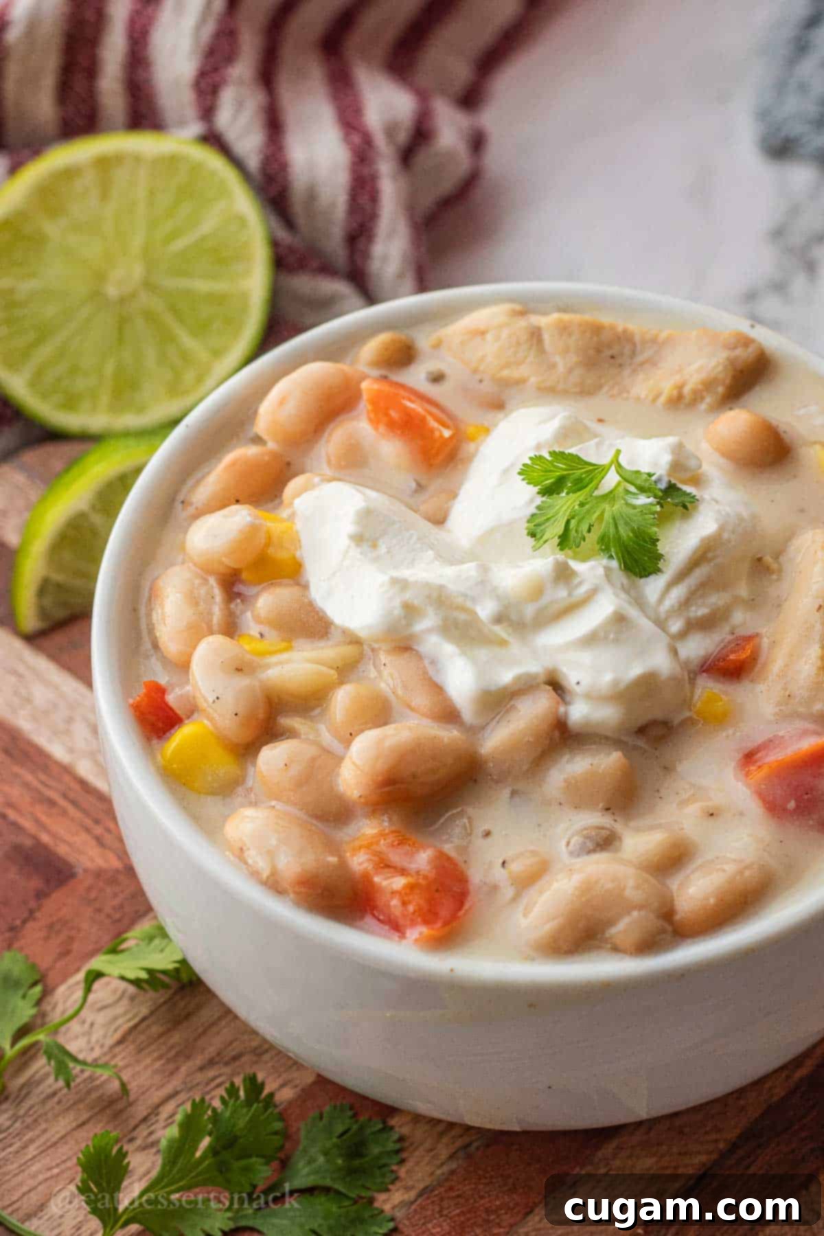 White bean chili in a white bowl with sour cream and cilantro.