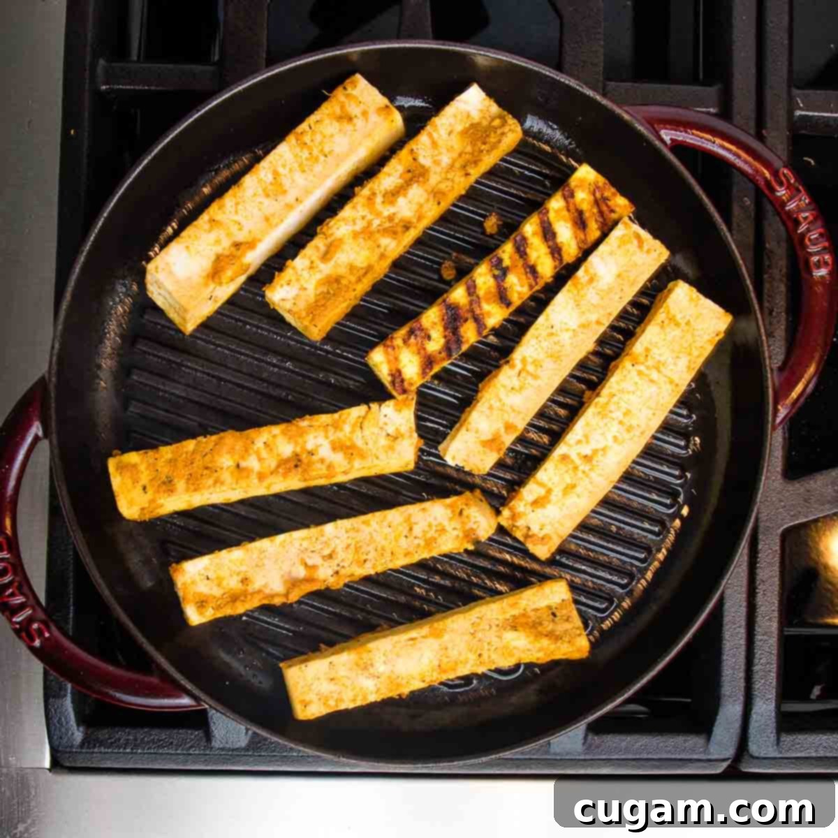 Round grill pan with tofu satay sticks.  One has been flipped to show grill marks. 