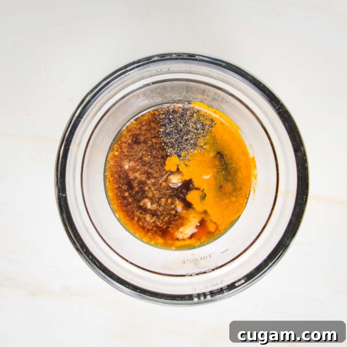 Tofu marinade ingredients in a small bowl: tamari, lime juice, maple syrup, garlic, ginger, turmeric and black pepper.