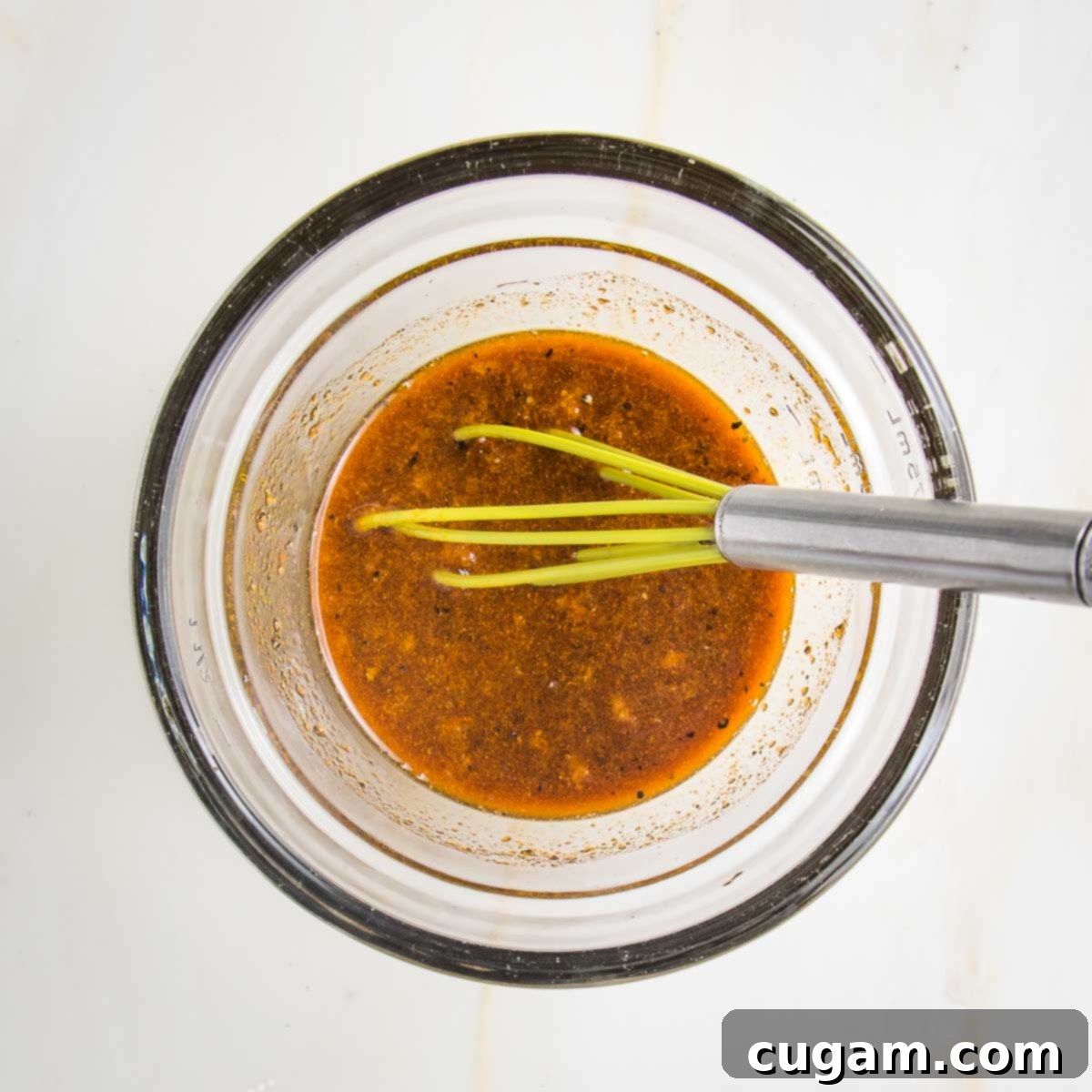 Tofu marinade ingredients whisked together in a small bowl. It's brown liquid with flecks of pepper, chunks of garlic and ginger and light yellowish color from the turmeric.