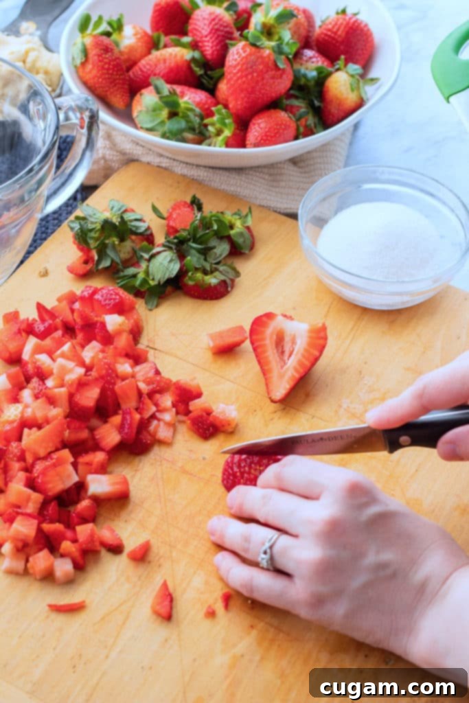 Fresh strawberries being chopped into a glass bowl with lemon juice and sugar for the filling.