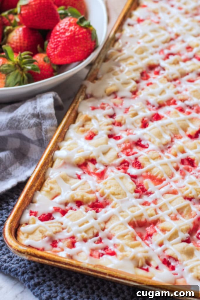Baked Strawberries and Cream Bars, perfectly golden, next to a bowl of fresh strawberries.