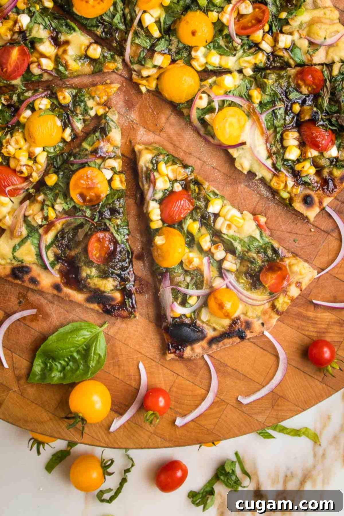 No yeast flatbread recipe, slathered with pesto and hummus and topped with fresh tomatoes, corn and onions.