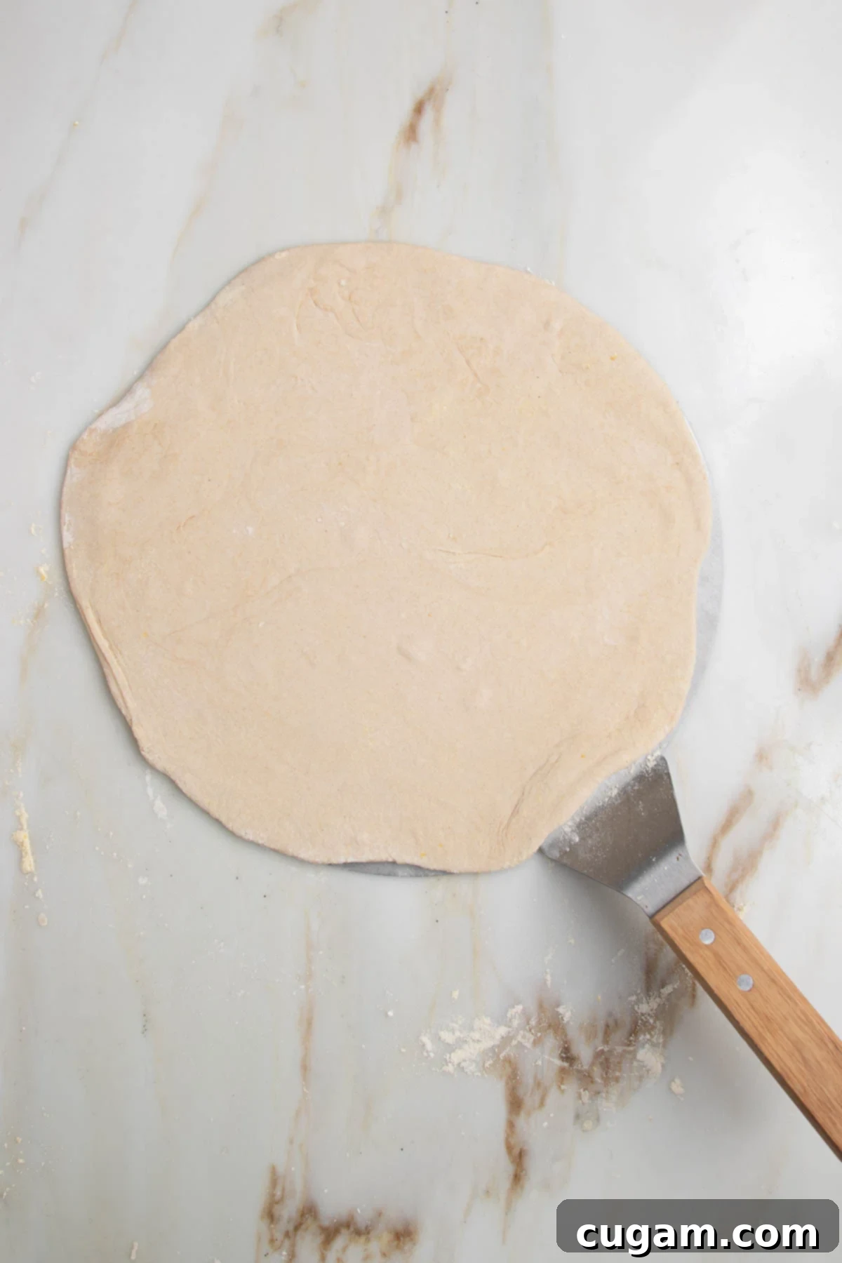 Flatbread pizza dough on top of a pizza peel.