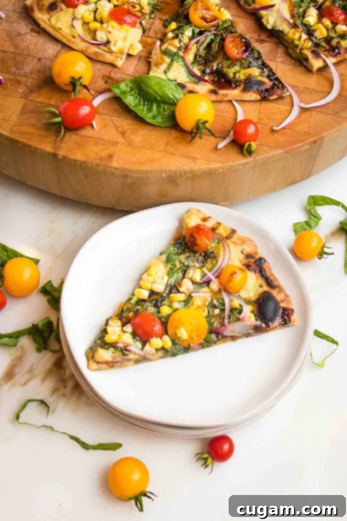 Slice of flatbread, topped with tomatoes, corn, onions and basil on a white plate. Remaining pizza slices are on a wooden cutting board.