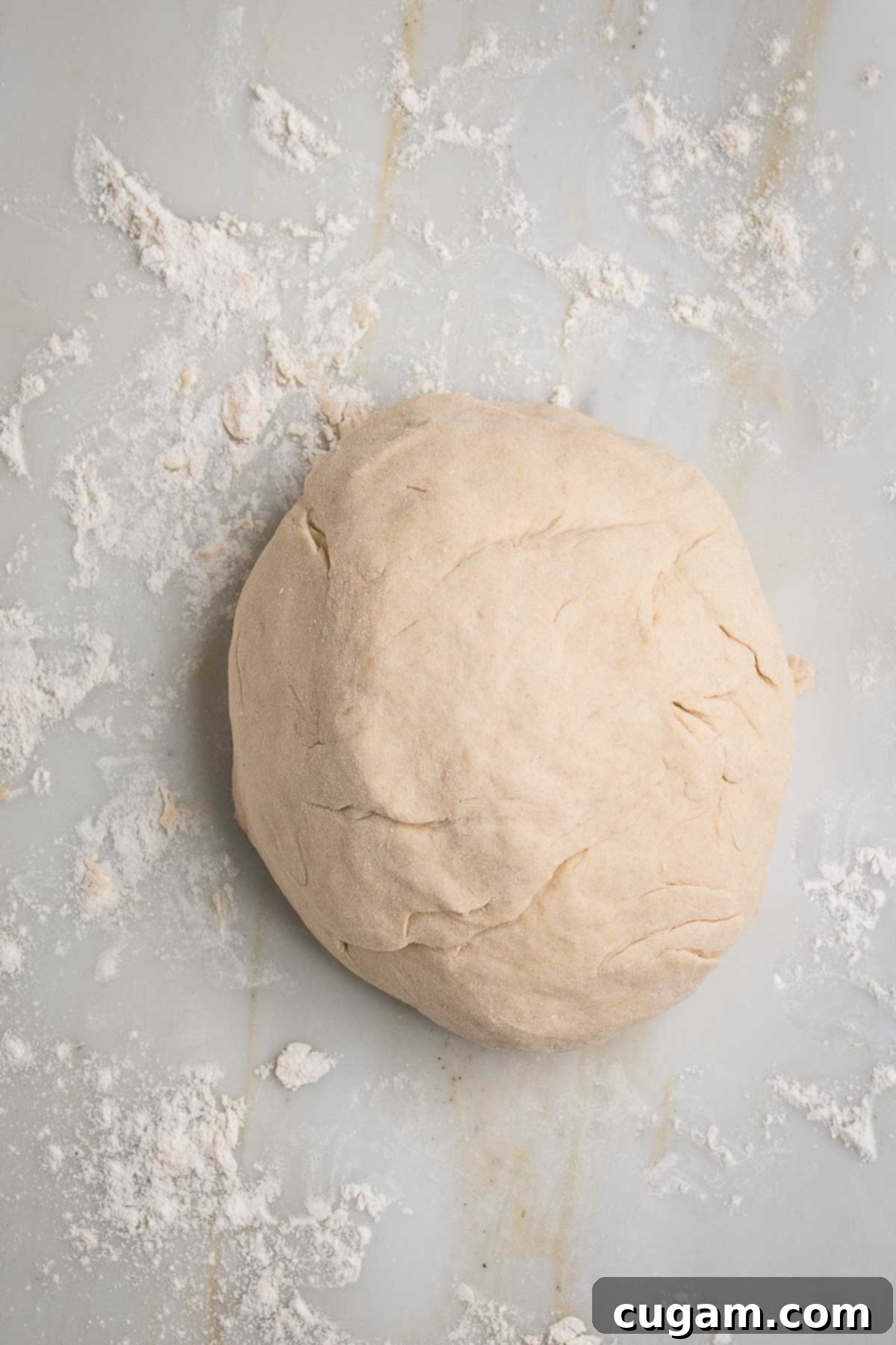 Large ball of dough on a floured marble counter.