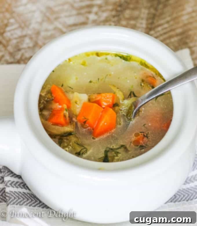 Bowl of Polish pickle soup with a spoon, sitting on a kitchen towel