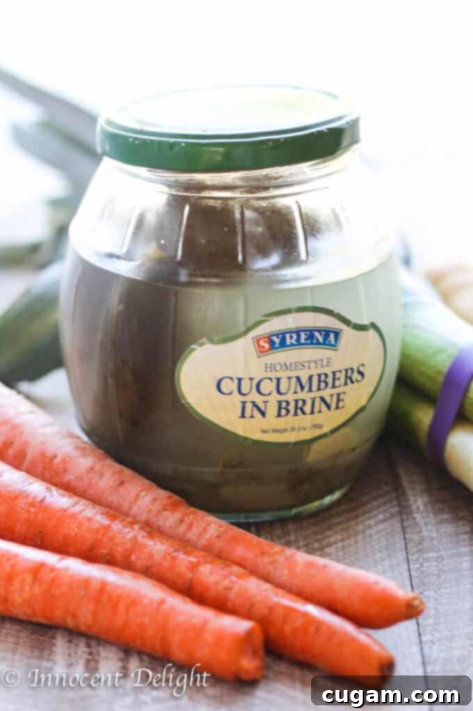 Jar of authentic brined Polish pickles with fresh carrots beside them