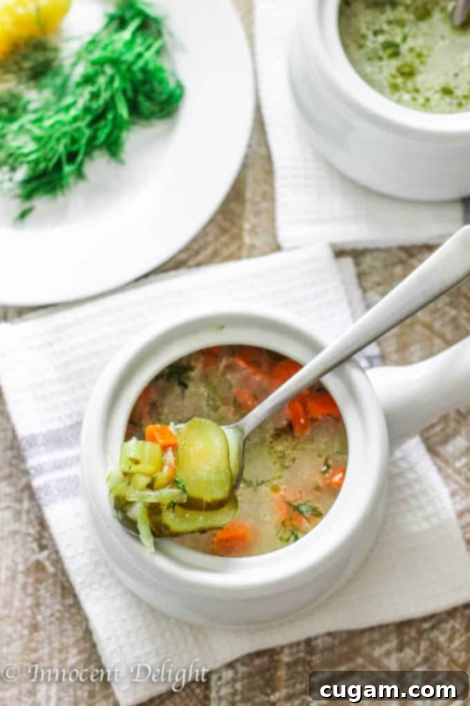 Two bowls of Polish dill pickle soup, one with a spoon showing the texture