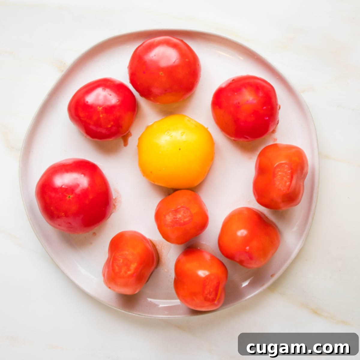 Tomatoes with their tops cut off, placed upside down on a plate to drain.