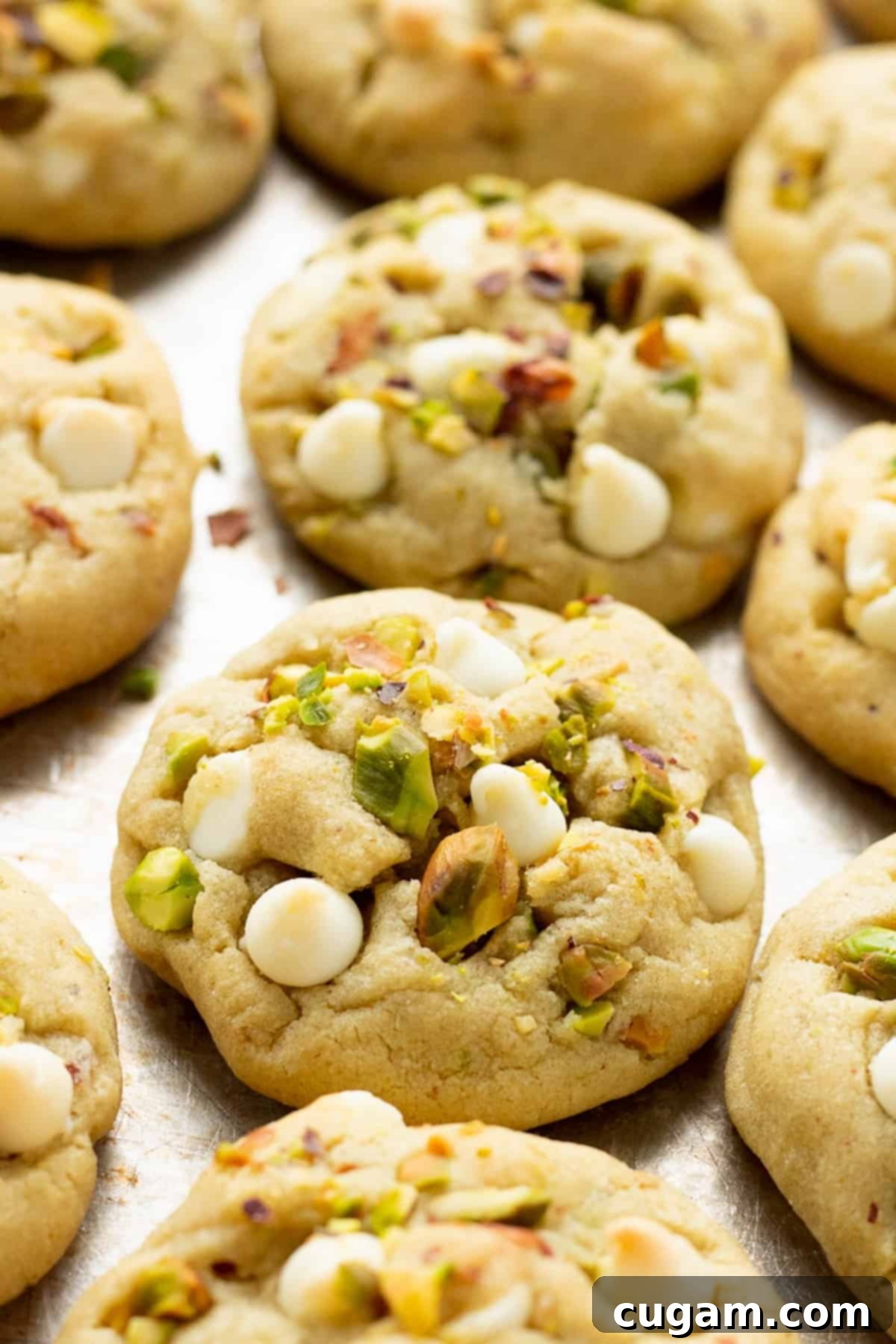 Freshly baked pistachio pudding cookies cooling on a metal baking sheet, showcasing their soft texture and green color.