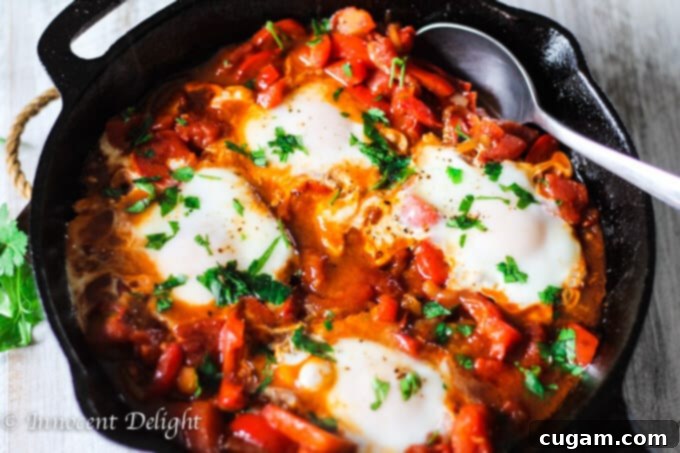Classic Mediterranean Shakshouka, a vibrant one-pan breakfast with poached eggs in a rich tomato sauce, garnished with fresh herbs.