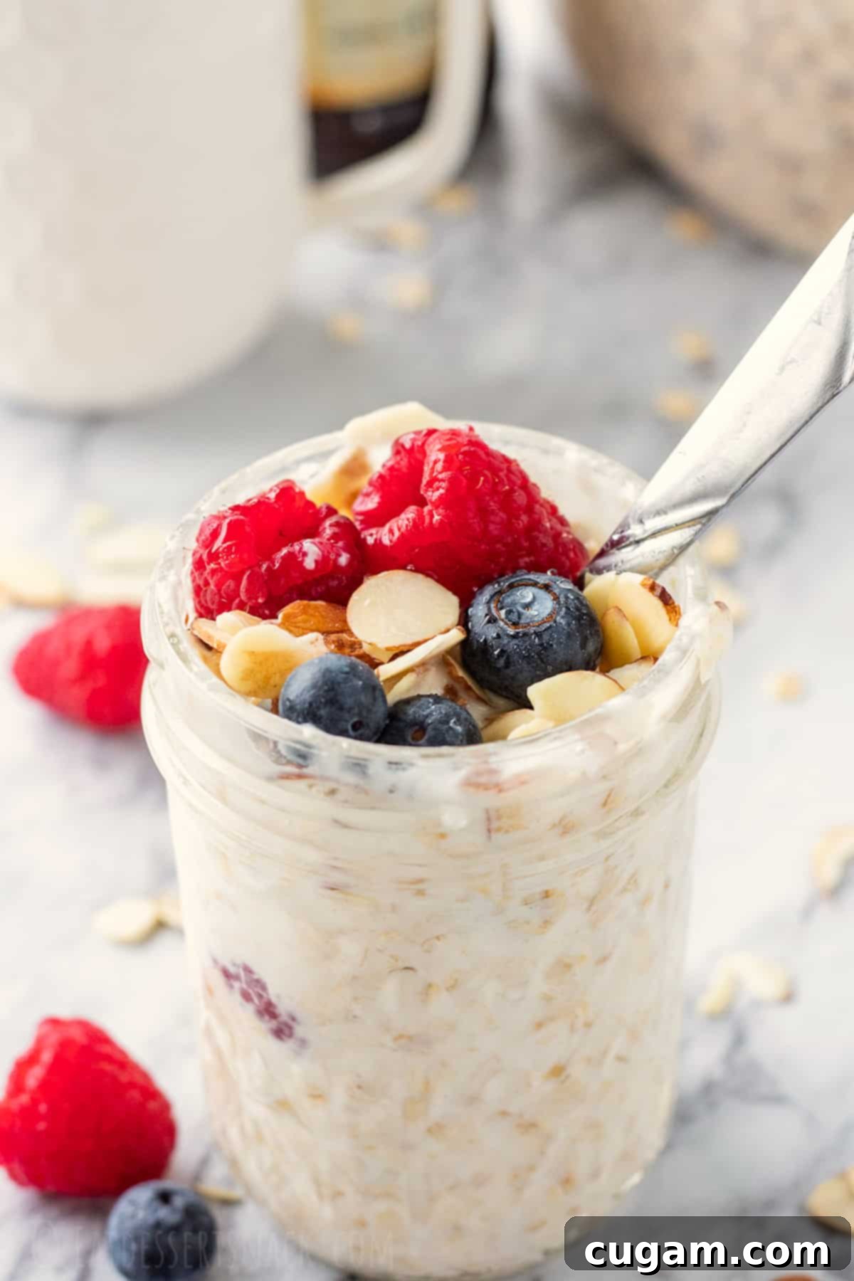 Jar full of vanilla overnight oats topped with fruit and a spoon.