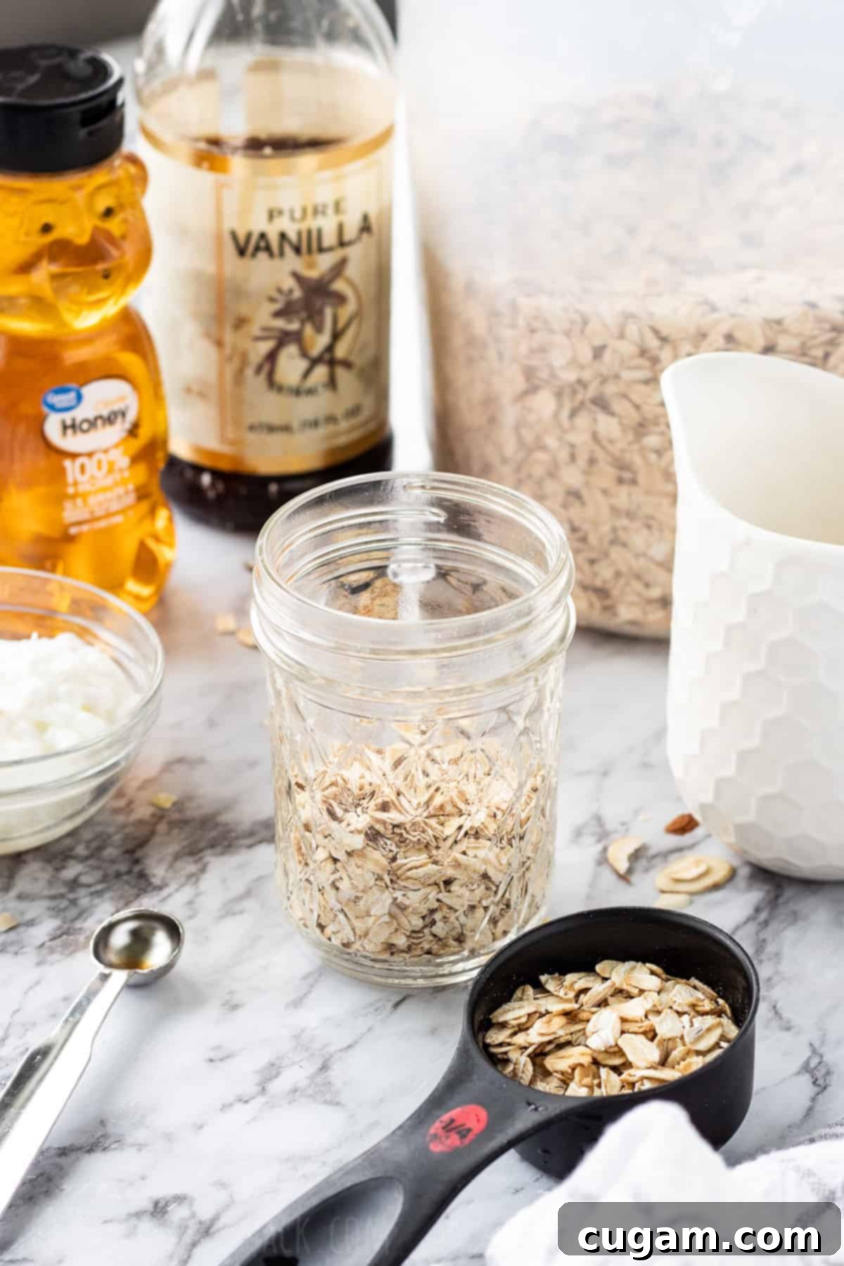 Dry oats in a jar with measureing cup, milk, and yogurt nearby in containers.