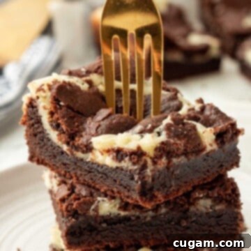 Stack of 3 baked cheesecake brownie bars with gold fork, showcasing the fudgy brownie and creamy cheesecake layers.
