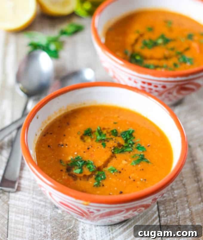 Two bowls of Tomatoes Red Lentils Coconut Soup  with spoons on a side, ready to be served