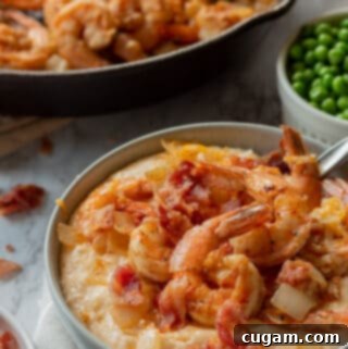 Cooked cheesy grits with shrimp, bacon and cheese on top in a gray bowl.