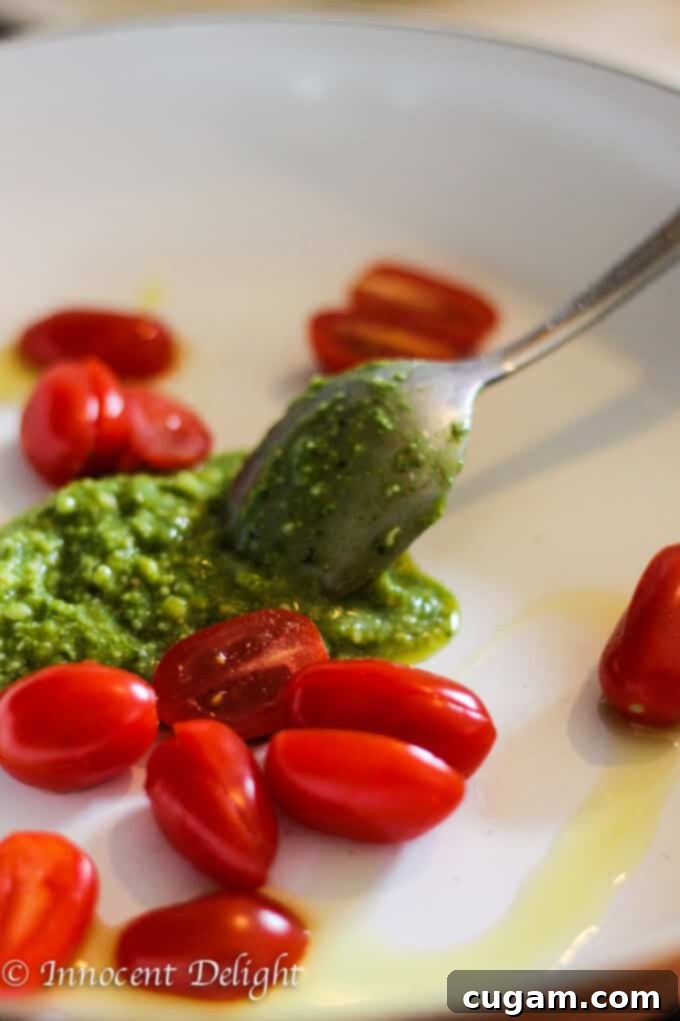 A bowl of freshly cooked Pesto Zucchini Noodles with Cherry Tomatoes, garnished with shaved Parmesan cheese.