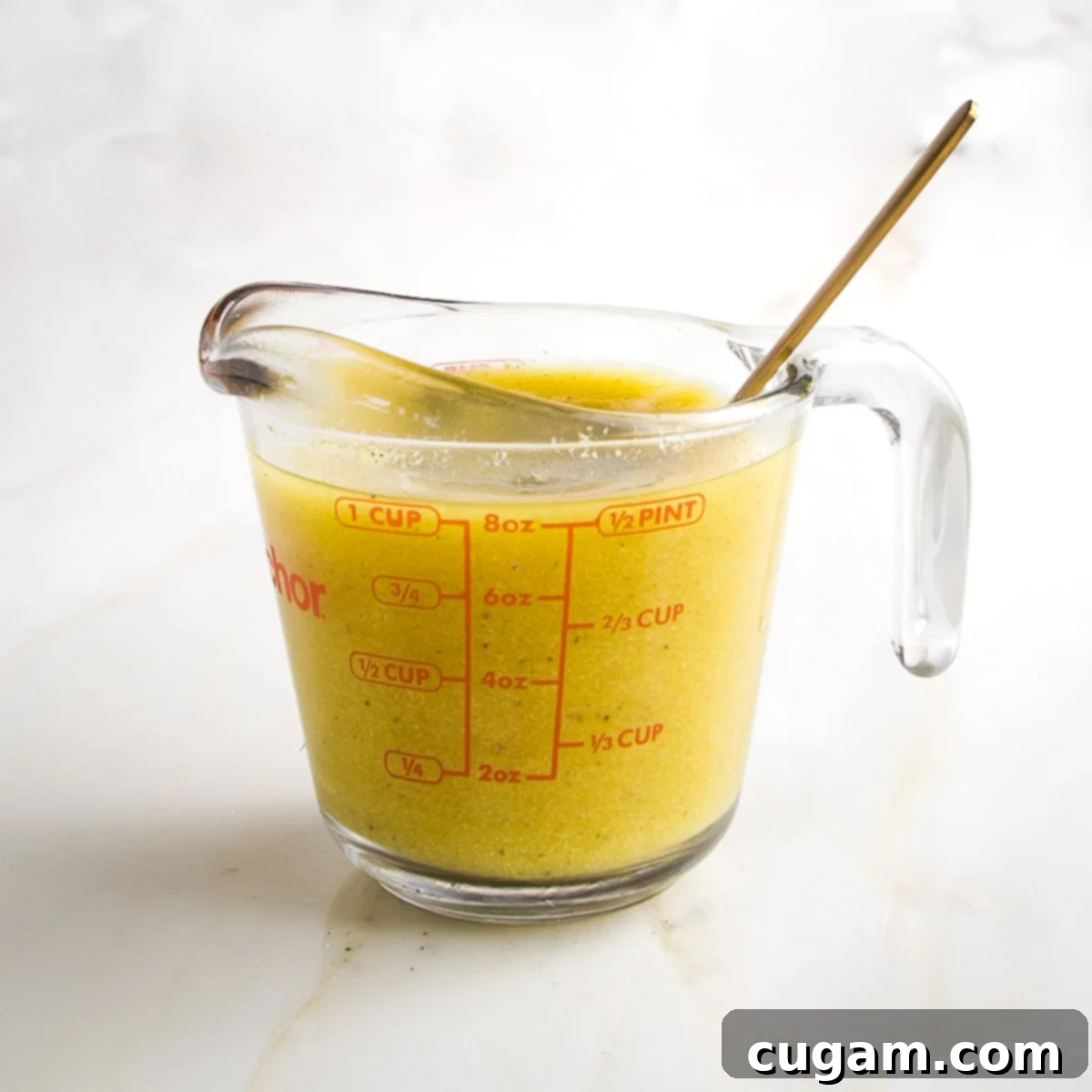 One cup pyrex measuring cup filled with yellowish broth. 
