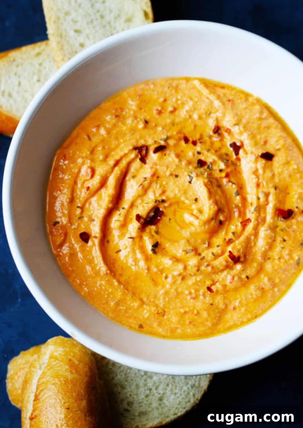 A beautifully presented bowl of creamy Greek Spicy Feta Dip (Tirokafteri) with a vibrant red hue, ready to be served as an appetizer.
