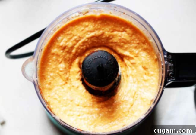 A close-up inside a food processor bowl, showing the creamy, blended Greek feta dip after processing, with a smooth, uniform texture.
