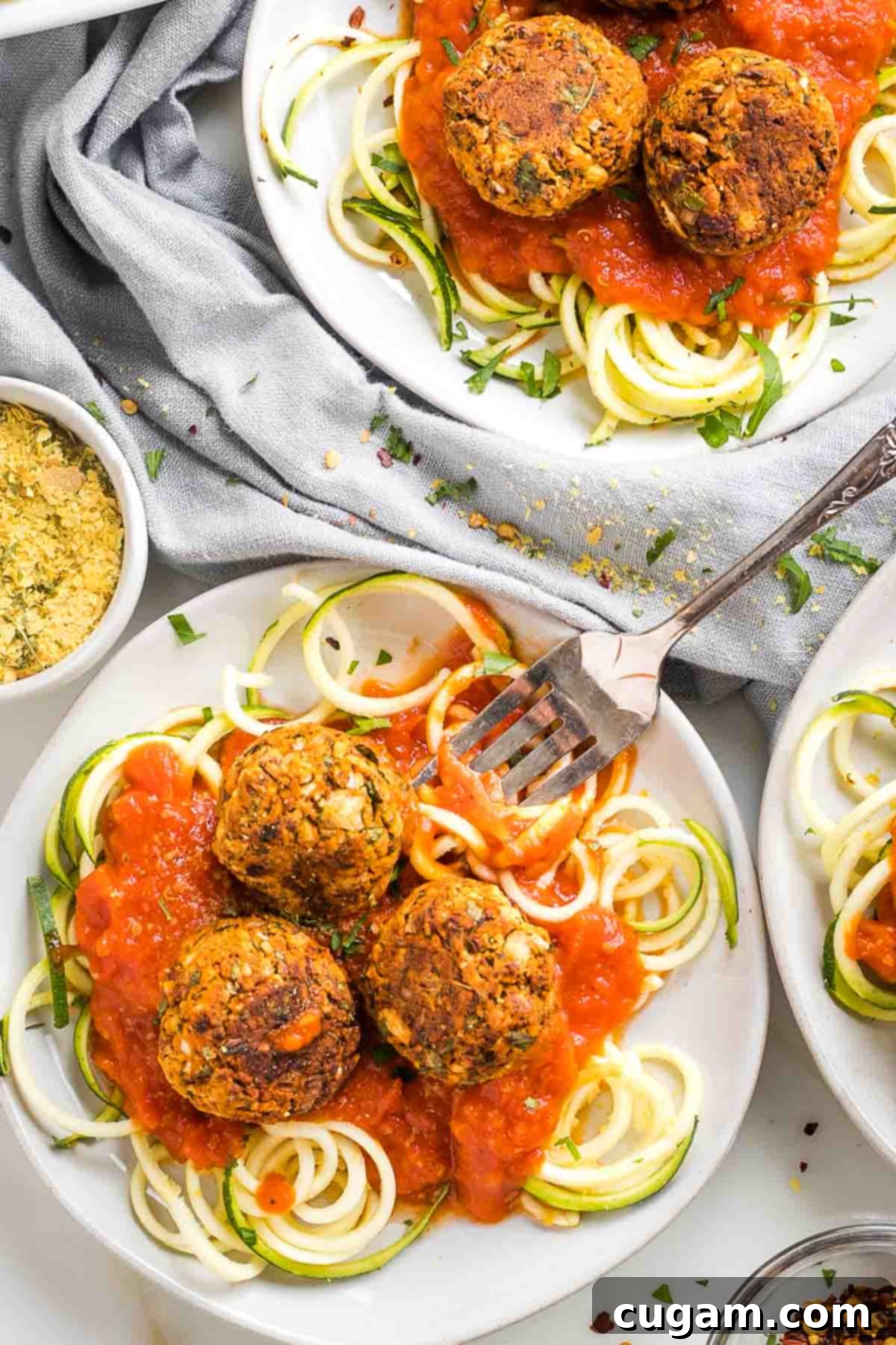 Plate of zucchini noodles with plant based meatballs on top of marinara sauce.