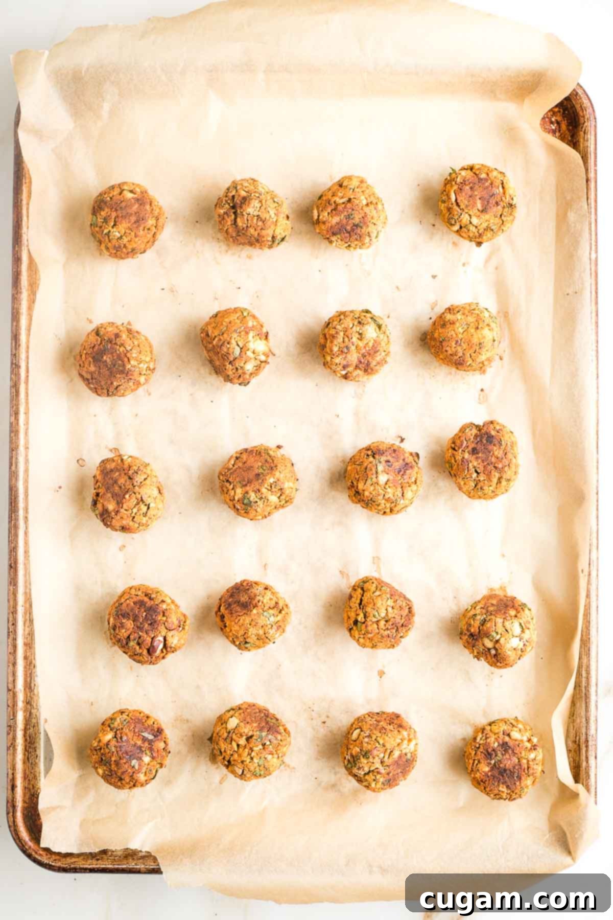 Baking tray with rows of cooked veggie balls.