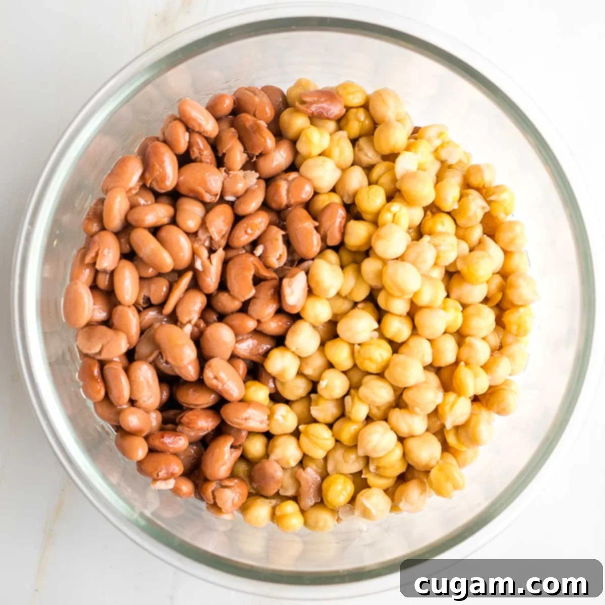 Pinto beans and chick peas in a glass mixing bowl.