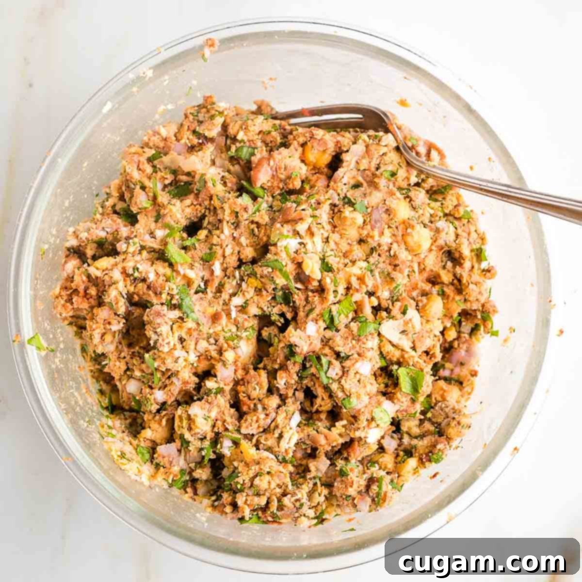 Mixing the vegan meatball batter with a fork until well combined and pasty.