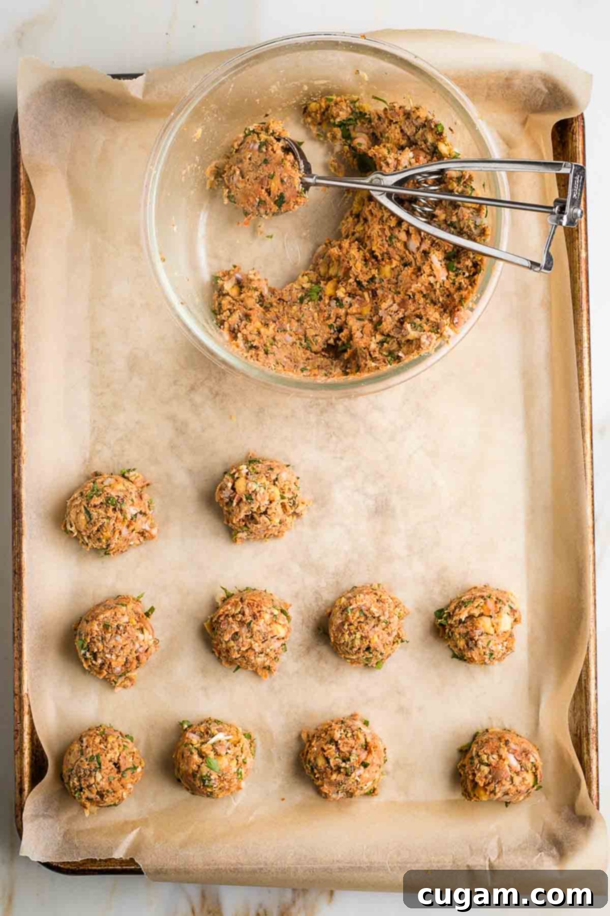 Scooping out portions of vegan meatball mixture with a cookie scoop.