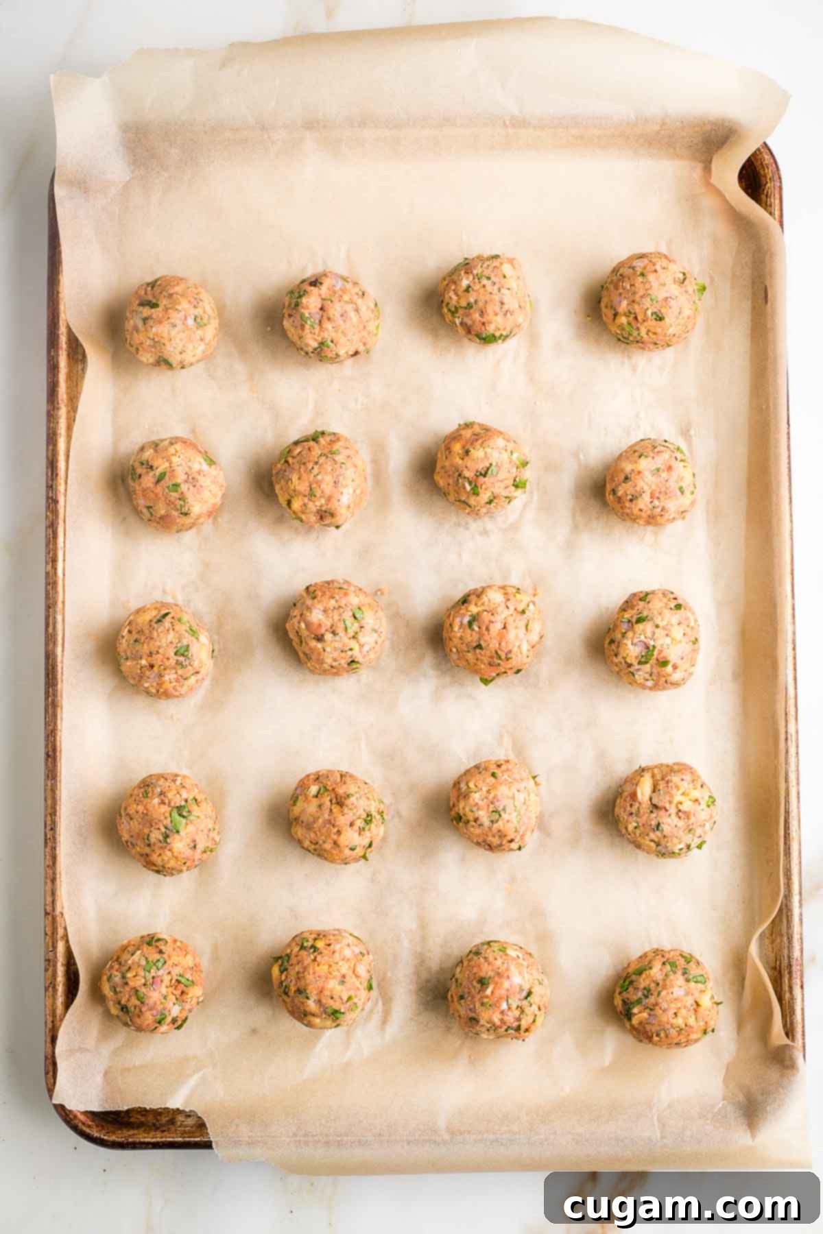 Veggie meatballs rolled into balls on a large baking tray with parchment paper.
