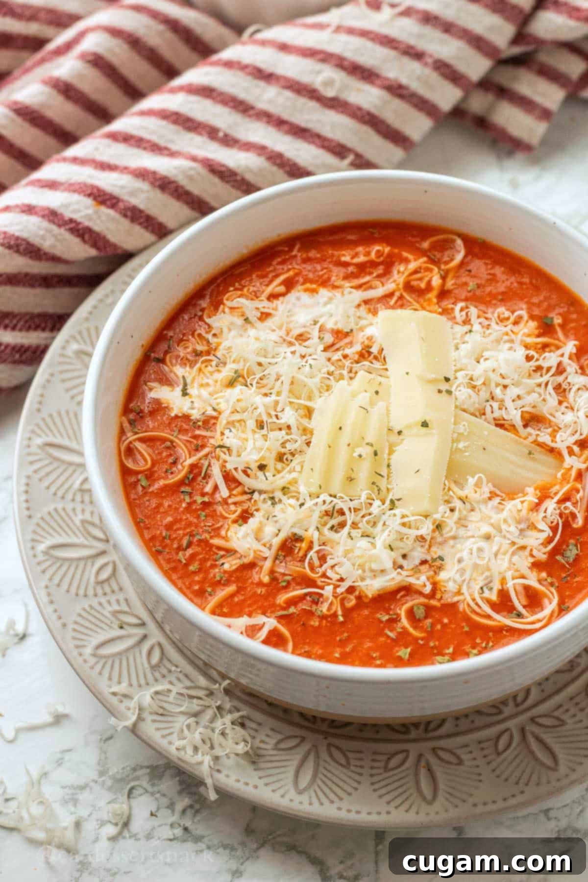 White bowl of cooked homemade bacon tomato soup in white bowl, garnished with fresh basil.