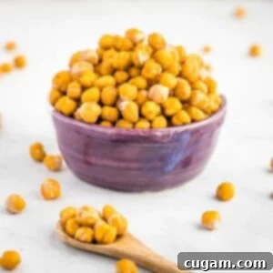 Crunchy chickpeas piled into a purple bowl with a spoonful of them in the foreground.