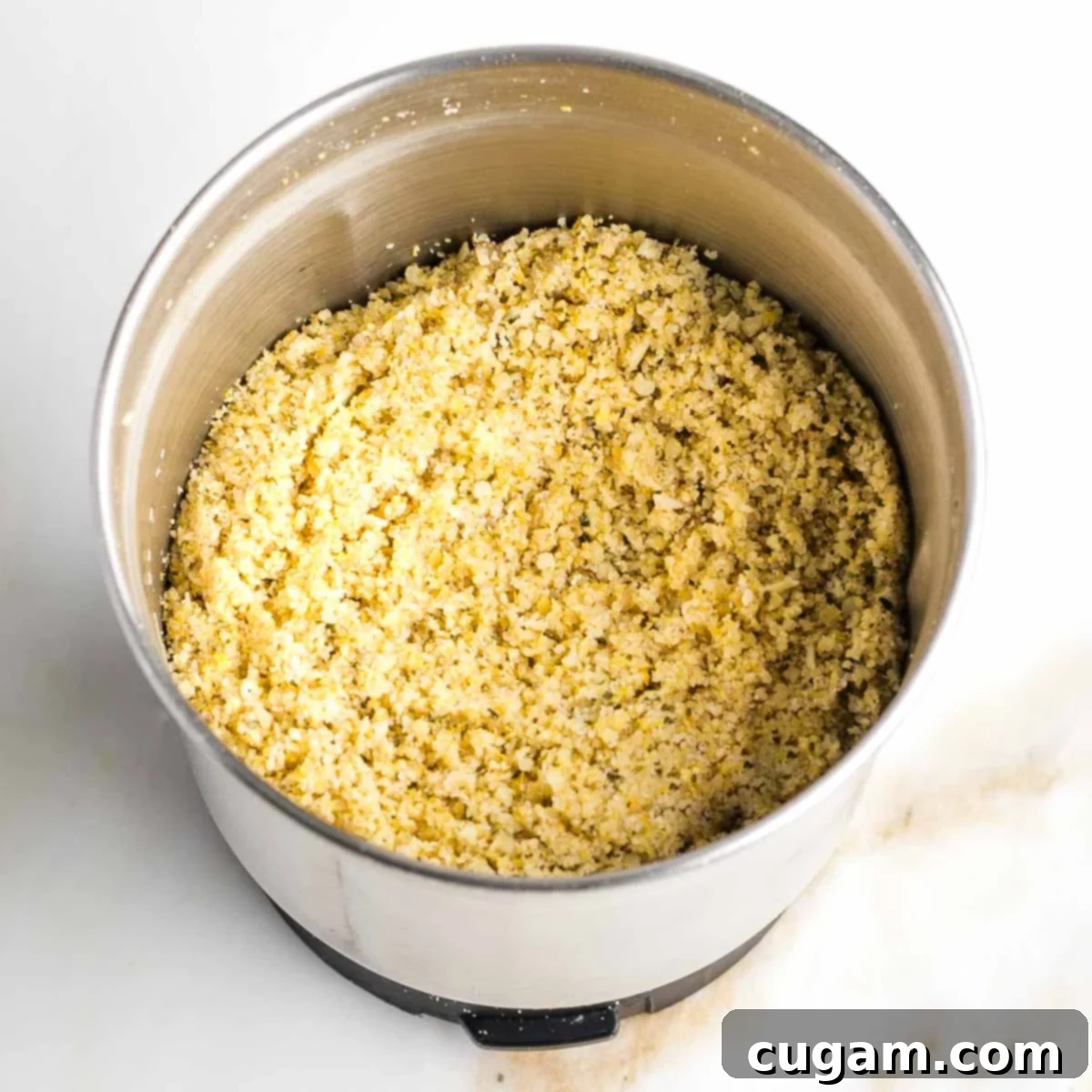 Spice grinder bowl with ground yellow powder that is dairy-free parmesan cheese.