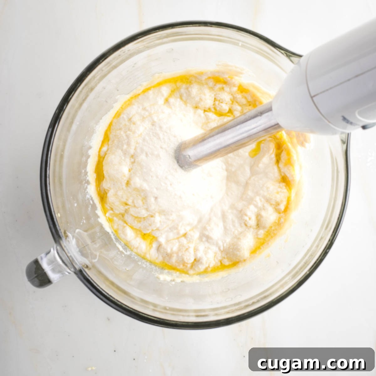 Immersion blender making mayonnaise in a glass measuring cup.