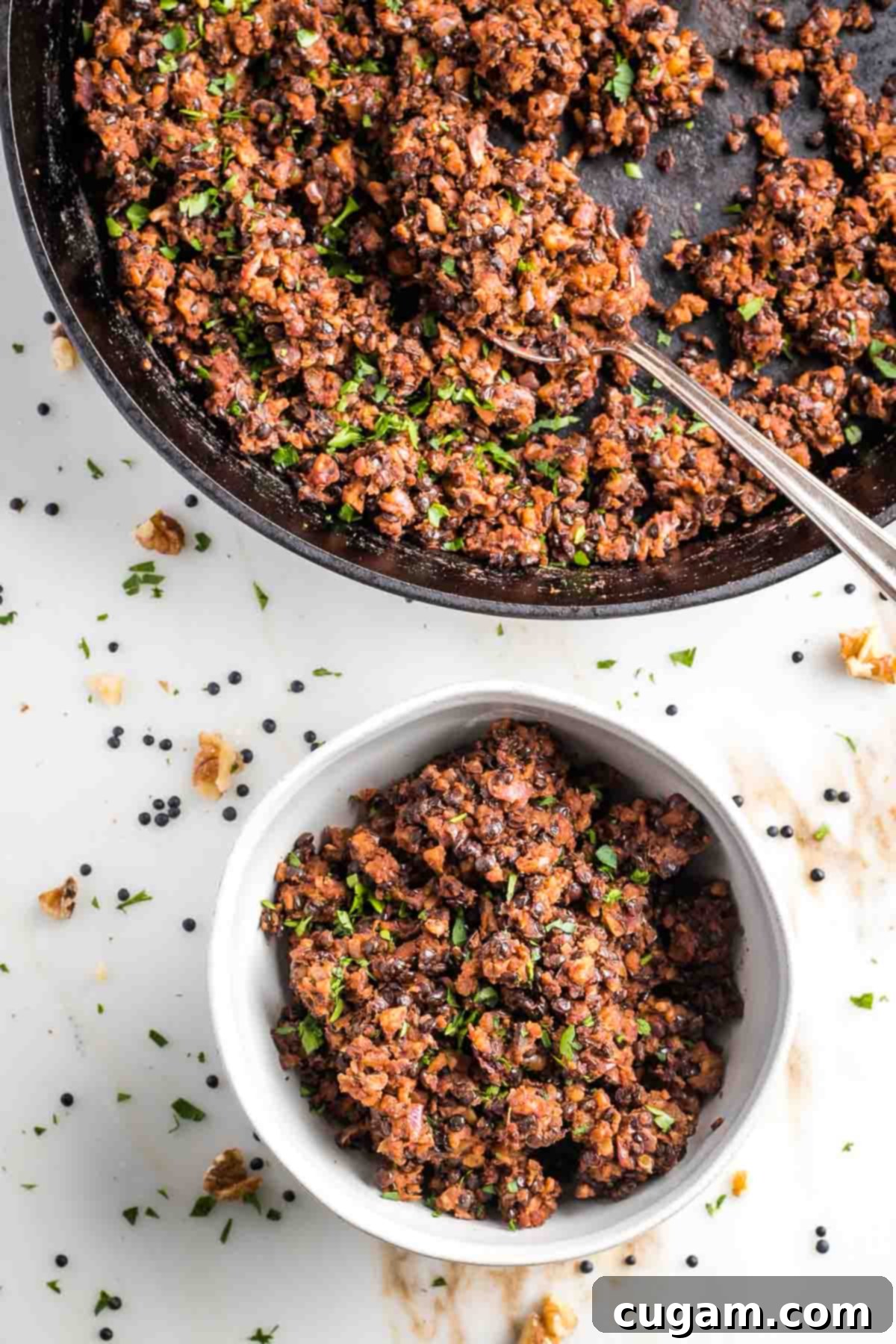Vegan ground beef in a cast iron skillet with spoon and a bowl of the meatless beef. 
