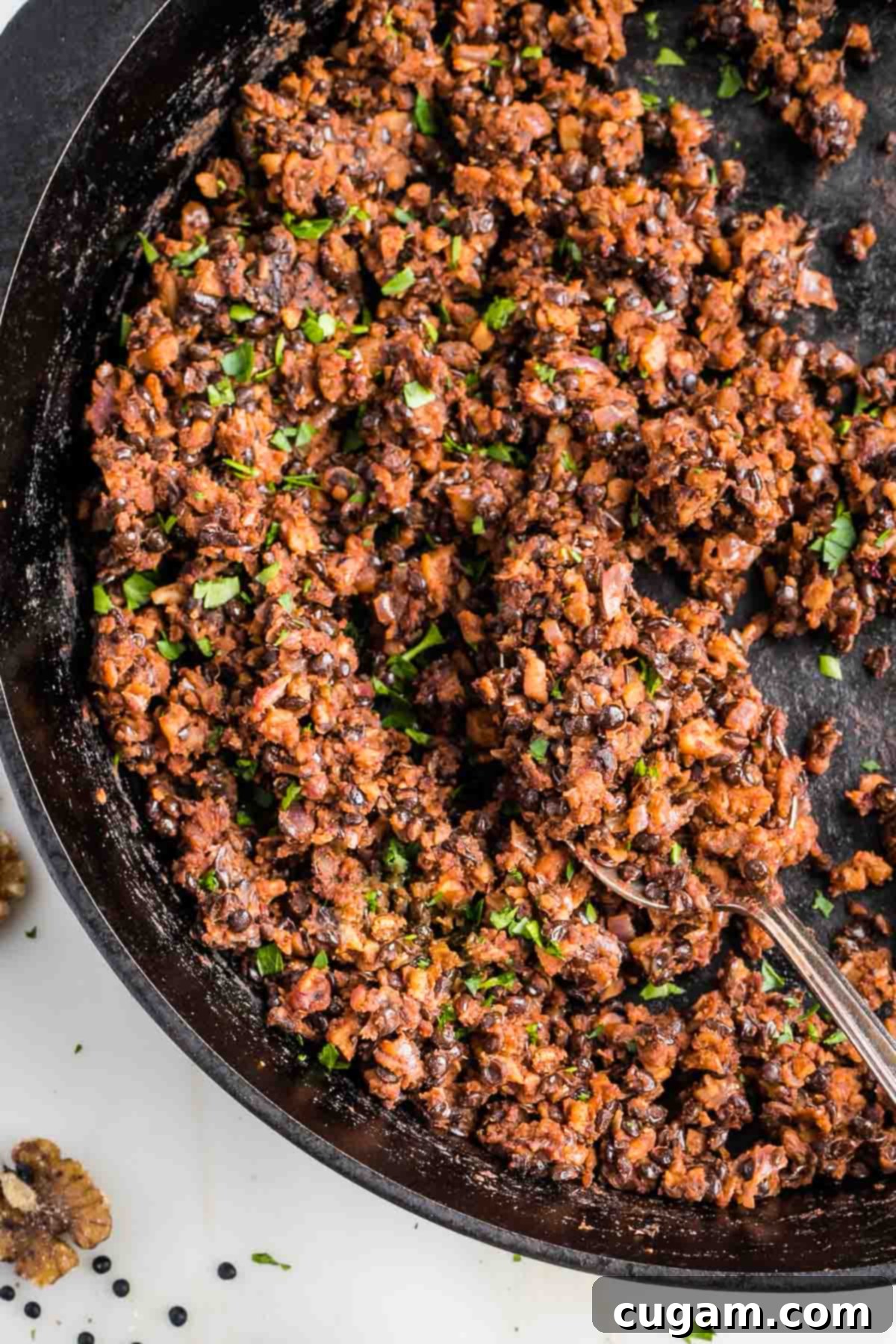 Vegan ground beef in a cast iron skillet, sprinkled with fresh chopped parsley.