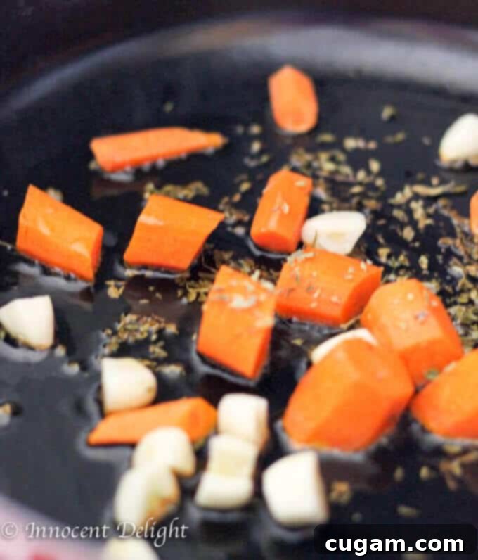 Sautéing garlic, carrots, and oregano for the tomato basil sauce base.