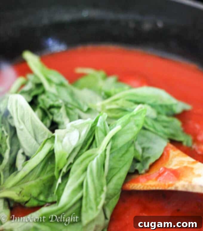Adding tomato puree to the sautéed vegetables to create the rich pasta sauce.